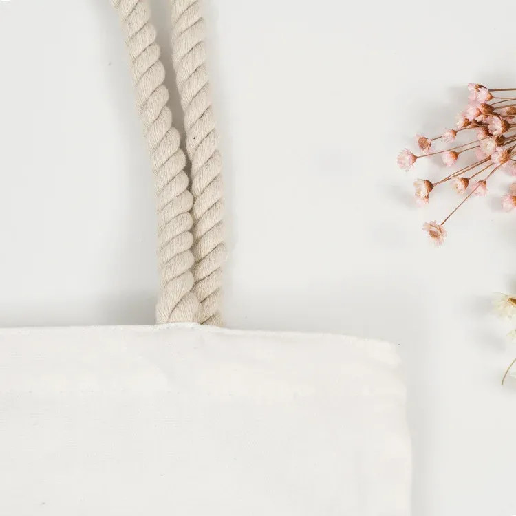 Close-up of twisted cotton rope handles attached to an ivory tote bag