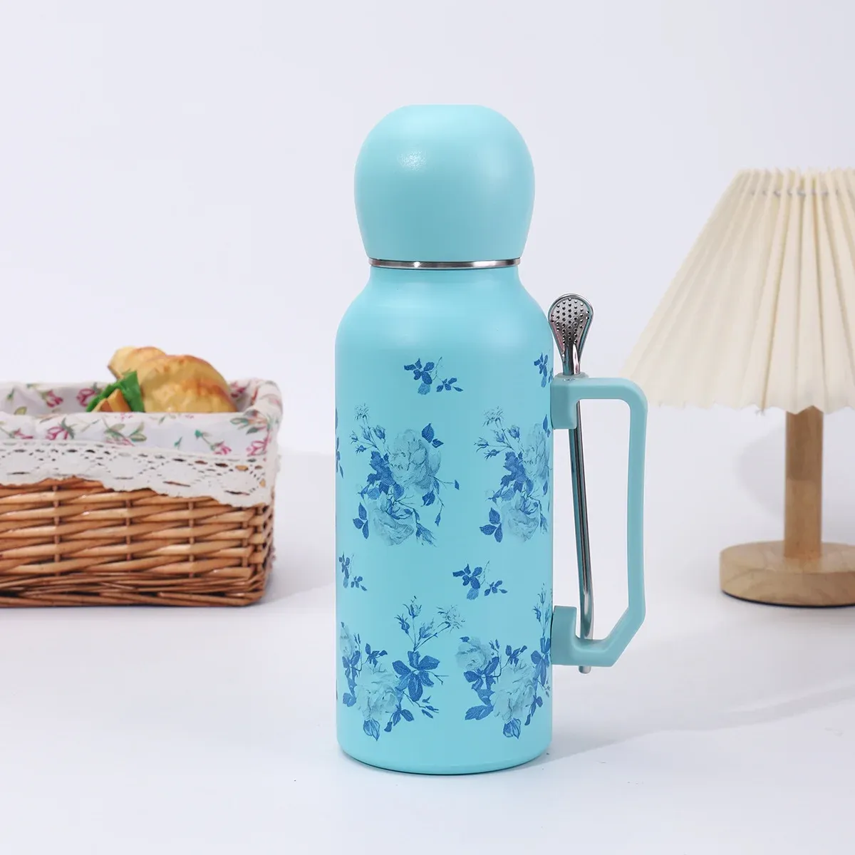 Light blue floral 1300ml vacuum bottle with matching dome lid, side handle and metal filter-spoon straw, lifestyle view