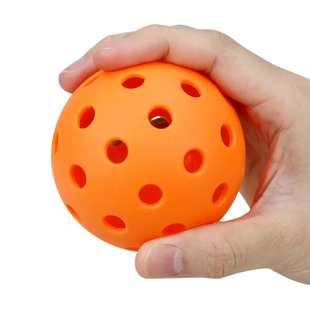 Orange TPE pickleball squeezed in one hand