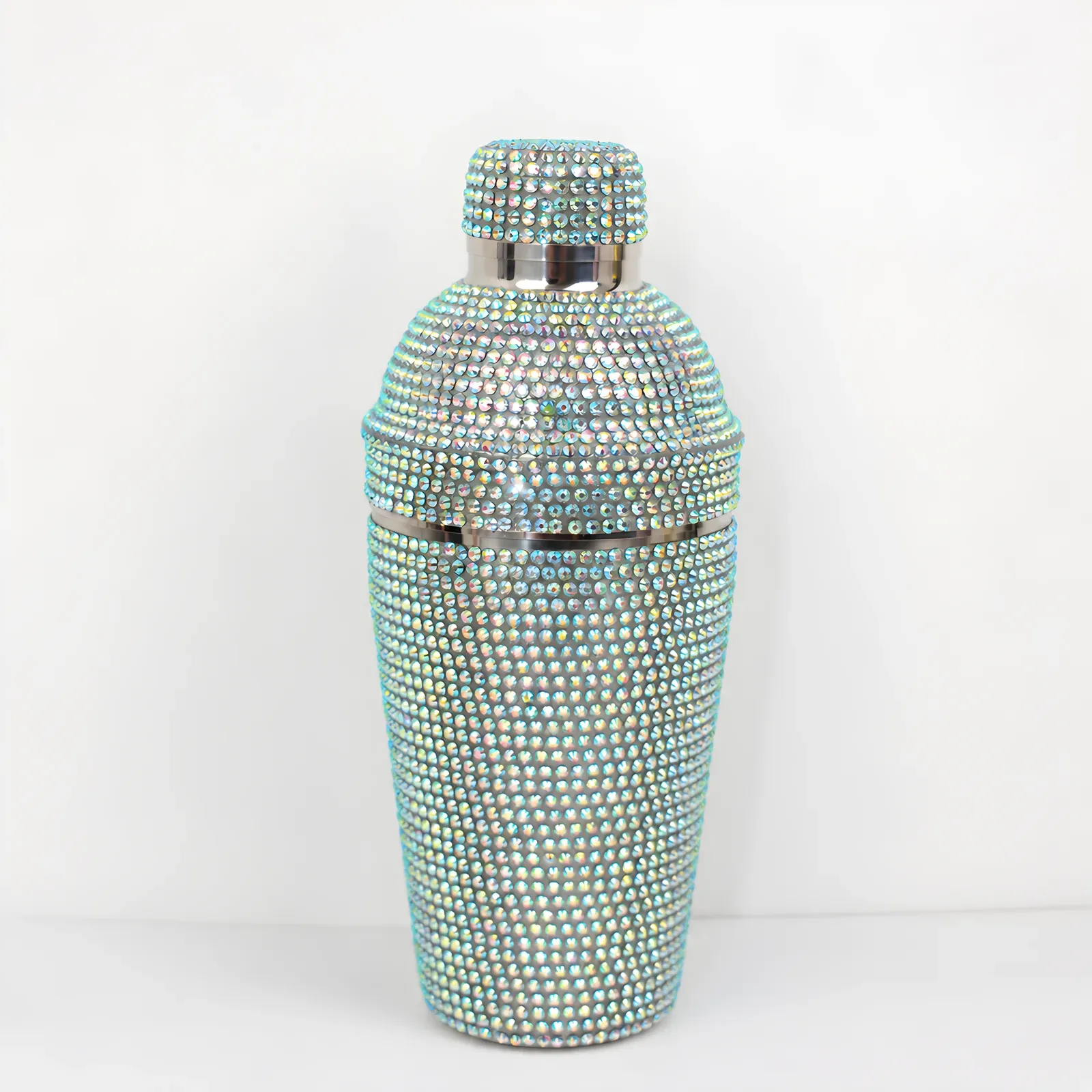 Cocktail shaker fully covered in iridescent abalone-effect rhinestones on a white background