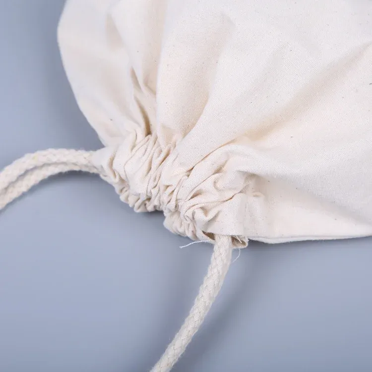 Close-up of the gathered drawstring top of a natural canvas pouch with braided cotton cord