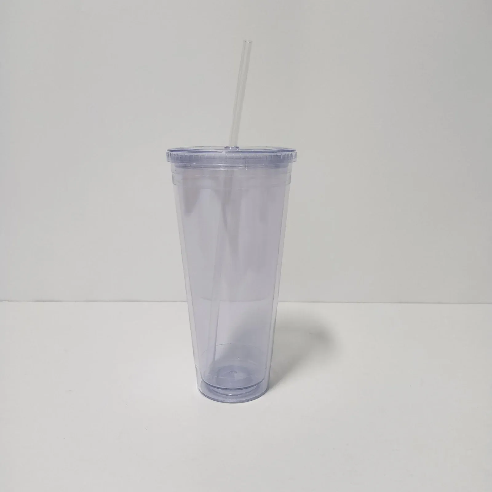 Clear double-wall plastic tumbler with flat clear lid and clear straw, no handle, front view on white background