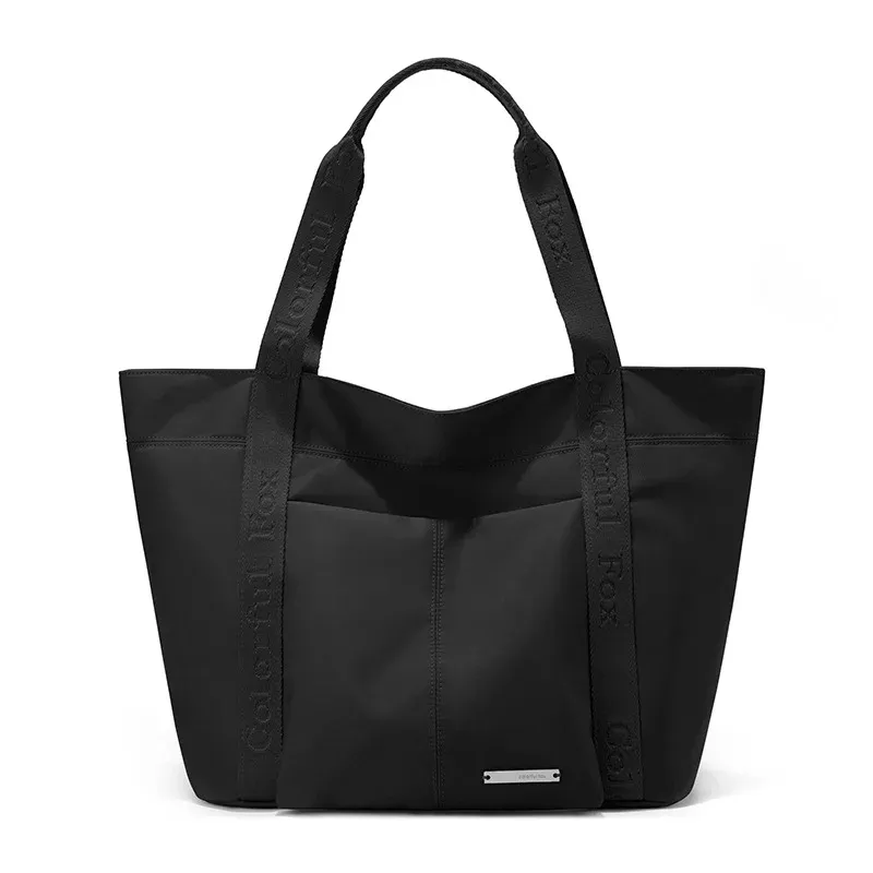 Black nylon tote bag with front slip pocket and short webbing handles with printed text, front view