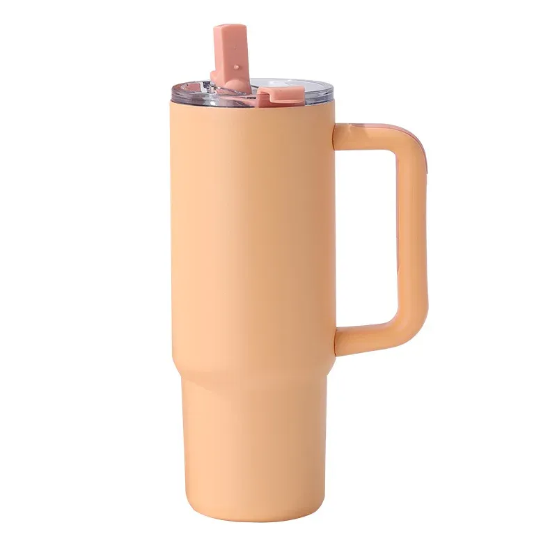 Warm yellow insulated tumbler with molded side handle, clear lid with pink straw tab, three-quarter view on white background