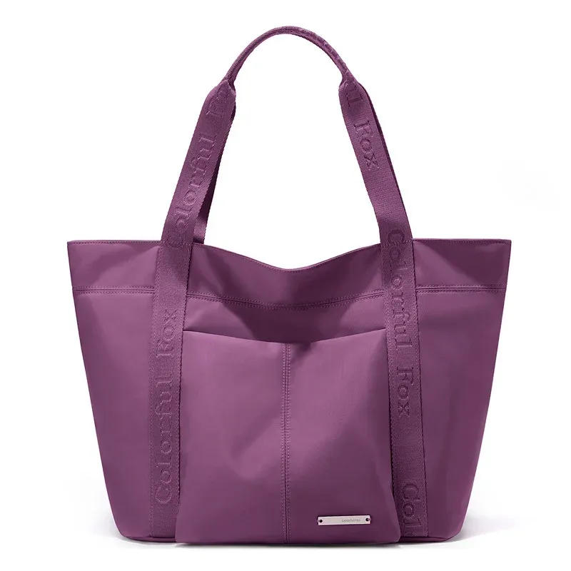 Purple nylon tote bag with front slip pocket and short webbing handles with printed text, front view