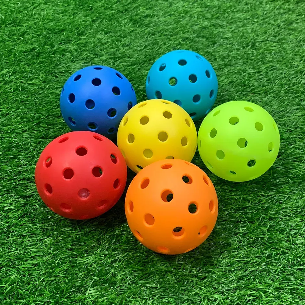 Six TPE pickleballs in mixed colors on turf