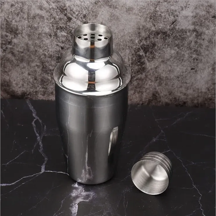 Silver stainless steel cocktail shaker with its cap removed, showing the built-in strainer