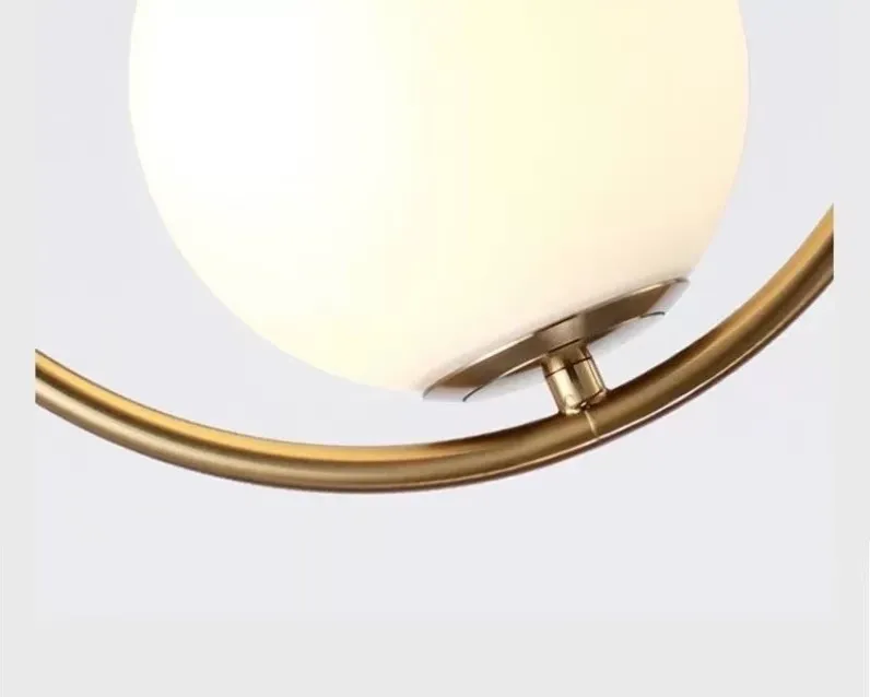 Close-up of brass metal frame and white glass globe shade connection on decorative pendant light.