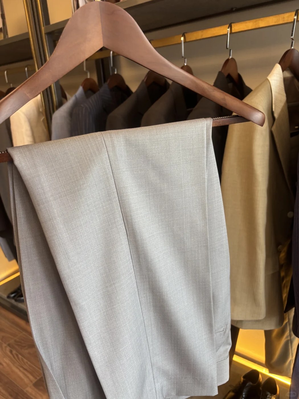 Beige suit trousers on wooden hanger