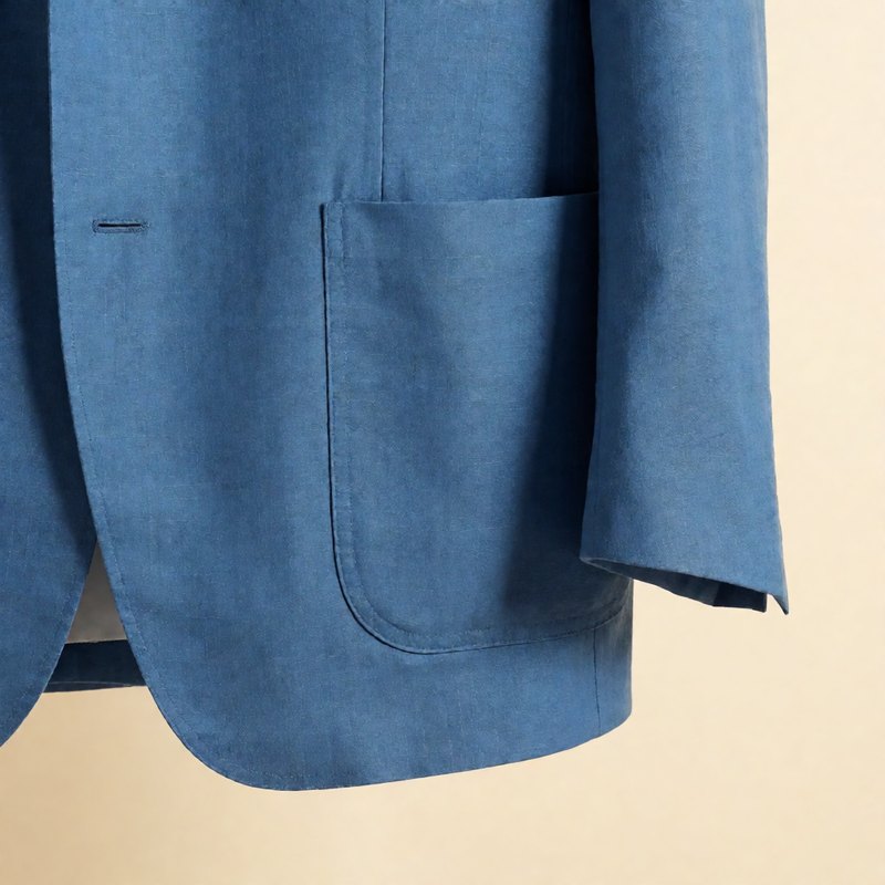 Close-up of the lapel and patch pocket in lake-blue silk-linen cloth