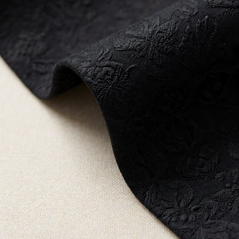 Macro of black tonal floral jacquard suiting fabric