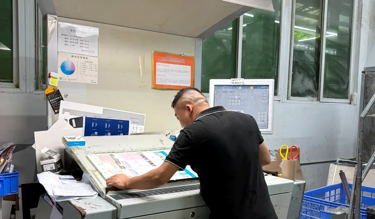 Printing press operator inspecting printed sheets at a factory quality control station
