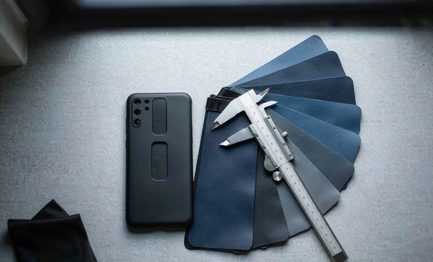 Phone case sample with colour swatch fan and caliper on a light work surface