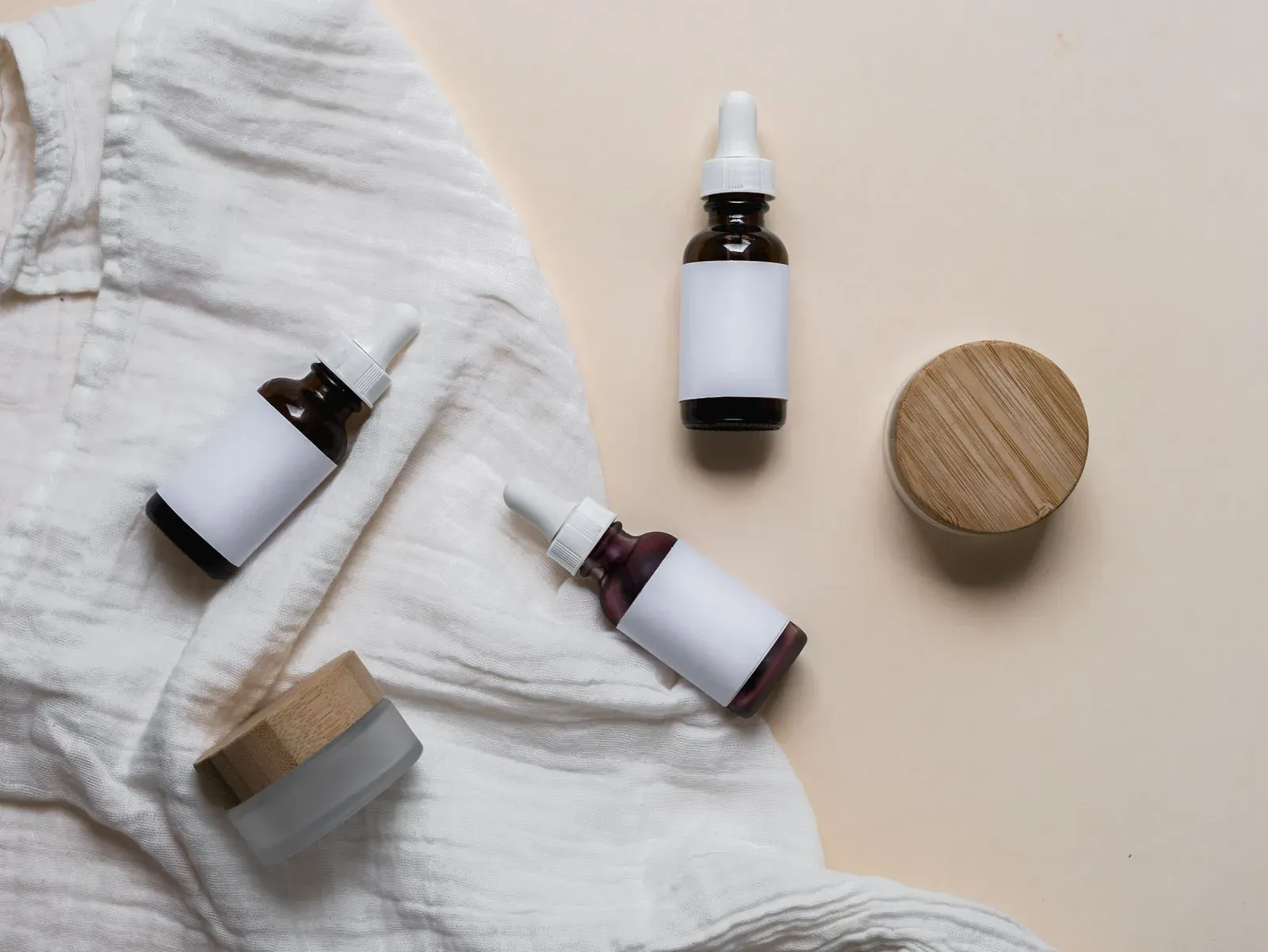 Glass skincare dropper bottles with custom printed labels on textured fabric, private label packaging branding