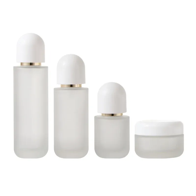 Four-piece frosted glass set with white dome caps: three bottles and a cream jar on white background