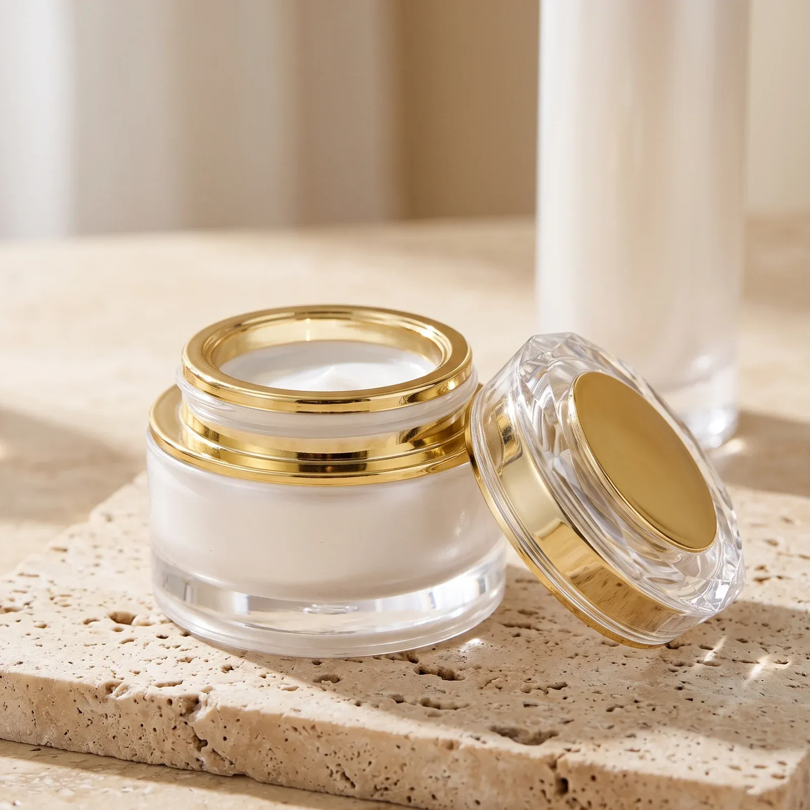 Open pearl-white glass cream jar filled with white cream beside its crystal-cut lid
