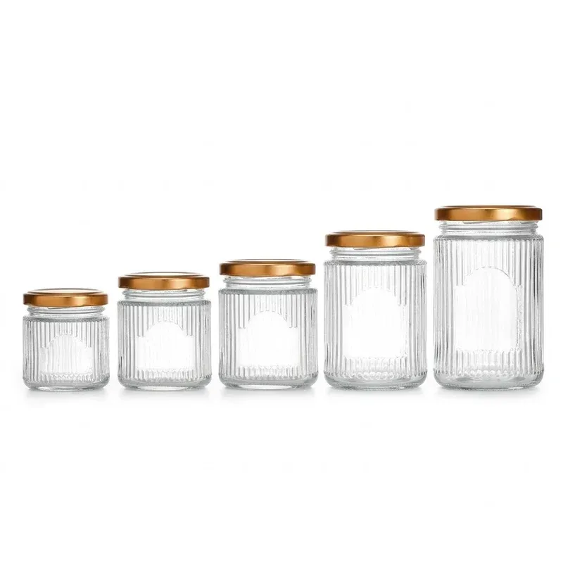Five ribbed glass jars of increasing size with gold lids and arched label windows, size family lineup