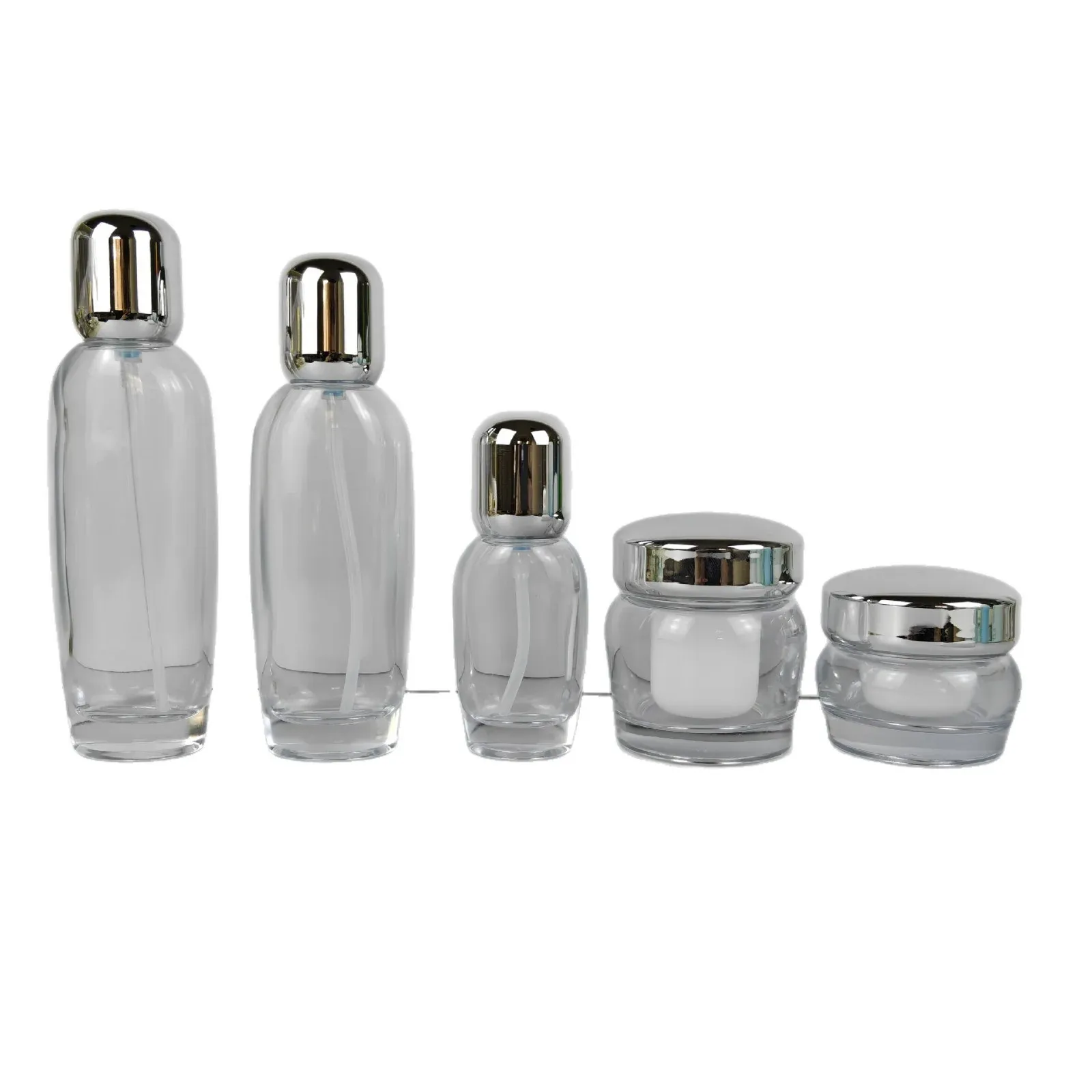 Five-piece clear glass set lineup: three bottles and two jars with silver caps