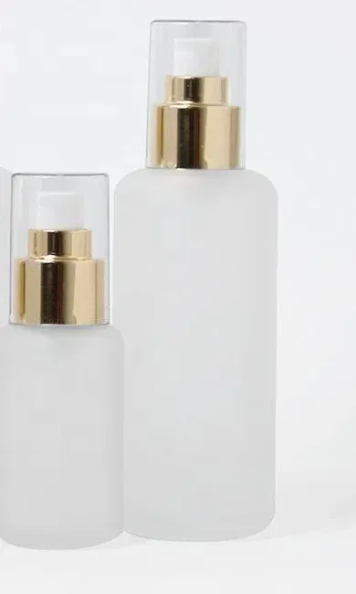 Two frosted glass spray bottles with gold collars and clear overcaps