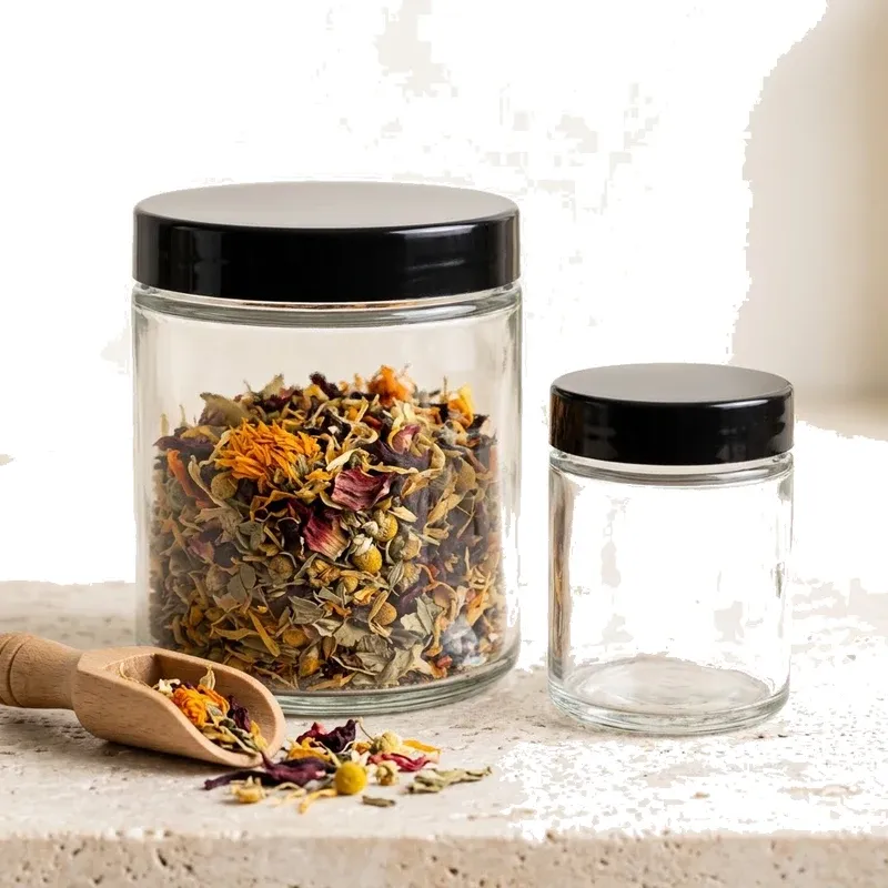 360 ml clear glass jar filled with floral herbal tea blend beside a 100 ml jar and wooden scoop