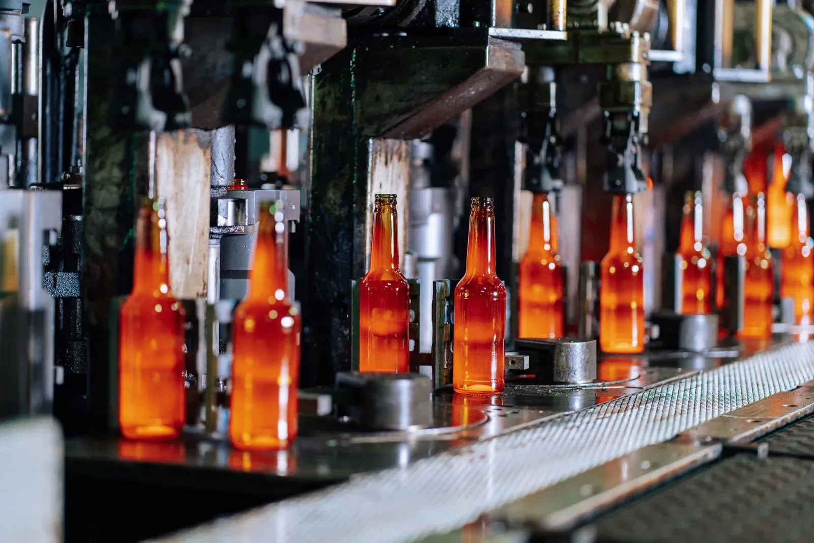 Glass bottles on a production line conveyor inside a factory, supplier audit context
