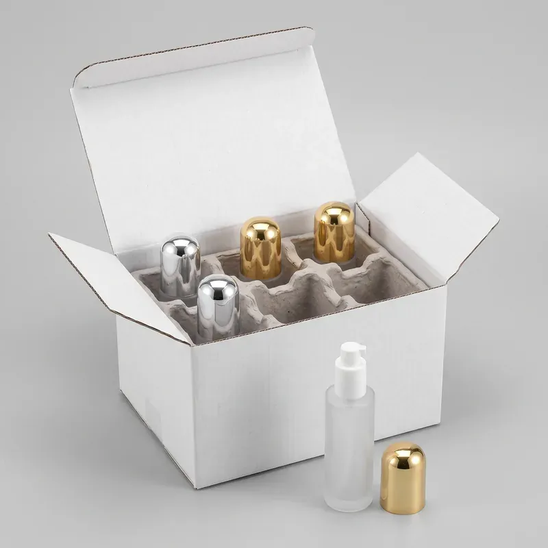 Frosted glass pump bottles with silver and gold dome overcaps export packed in a molded pulp divider inside a white shipping carton