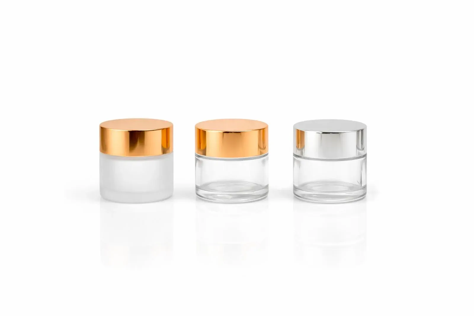 Clear glass cosmetic jars with metallic lids on a white background for a cosmetics line