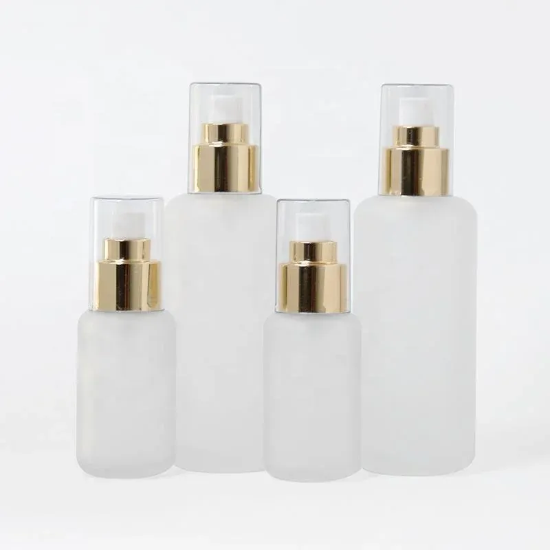 Four frosted glass spray bottles with gold collars and clear caps