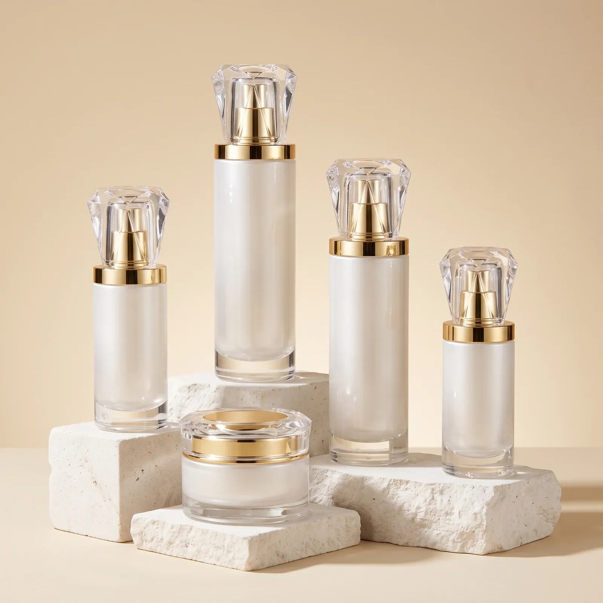 Pearl-white coated glass bottles with faceted crystal-clear caps and a matching crystal-lid cream jar on travertine cubes