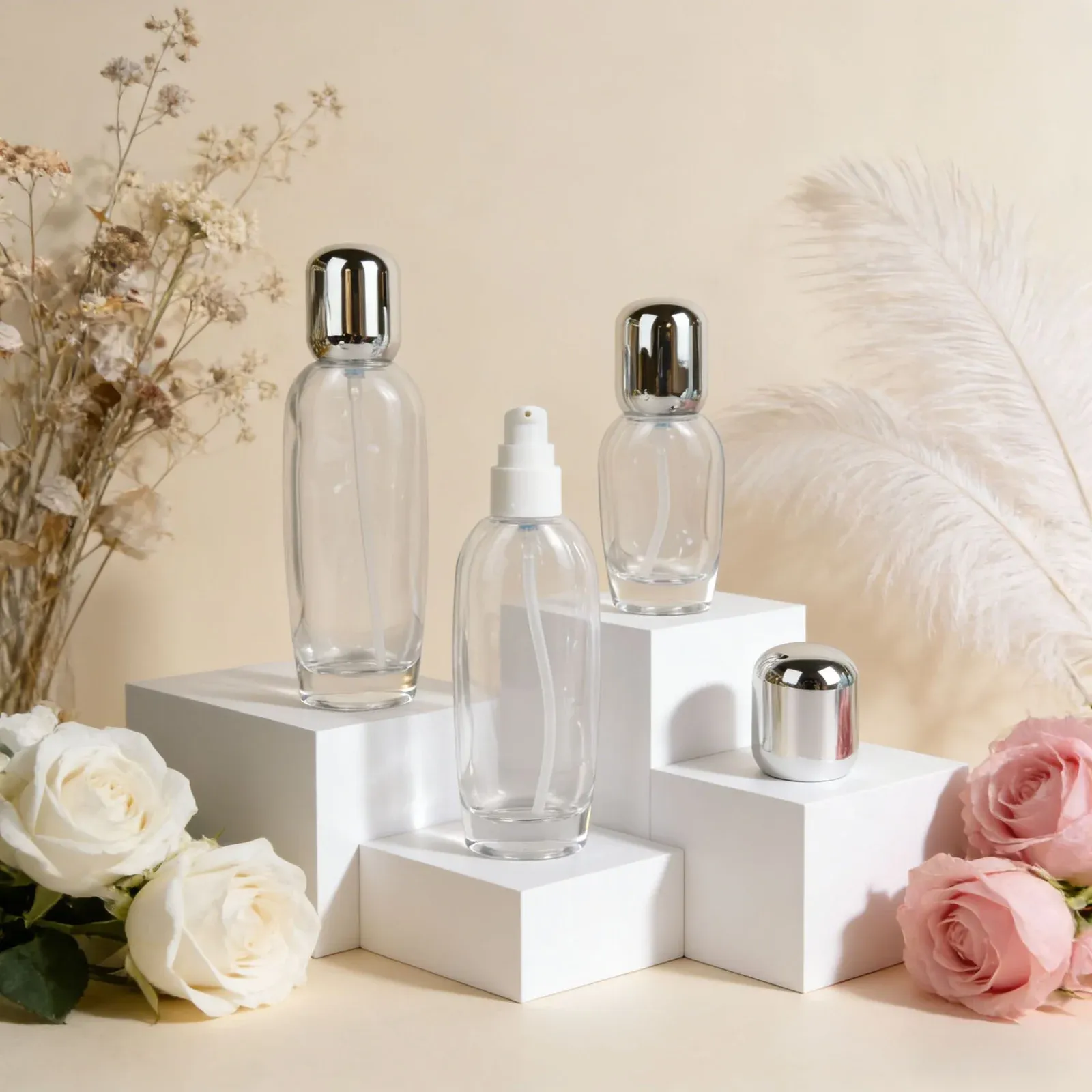 Clear glass skincare set with silver dome caps: pump bottles and a cream jar on white podiums with roses