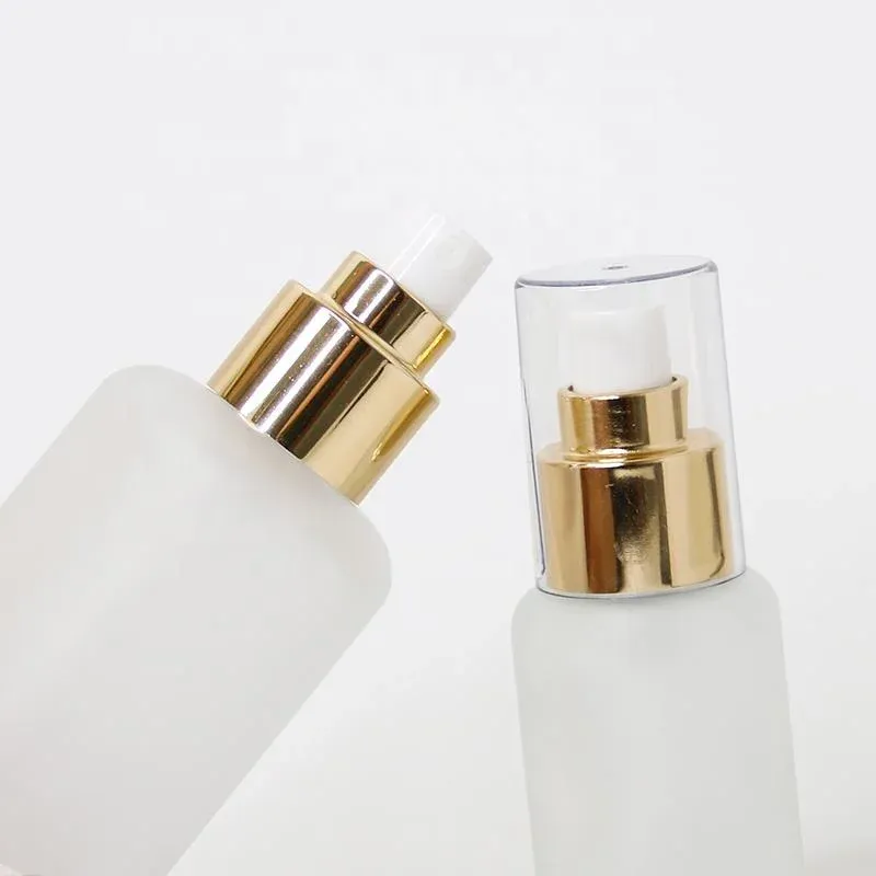 Close-up of gold spray pumps with clear overcaps on frosted glass bottles