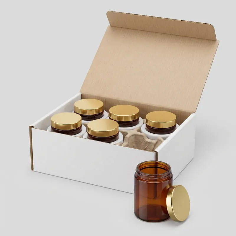 Amber straight-sided glass jars with gold lids export packed in a white carton with foam rings and a molded pulp divider, one open sample jar in front