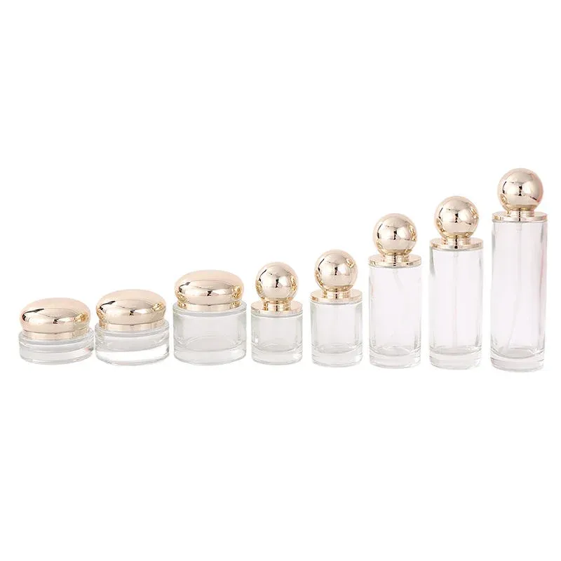 Eight-piece clear glass set with gold ball lids: cream jars and bottles in ascending size order
