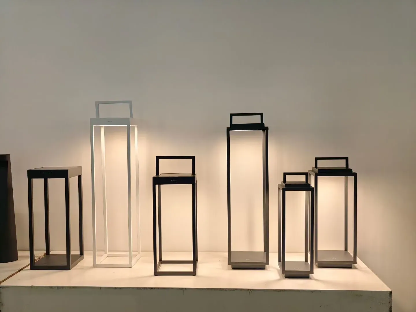 Portable garden lanterns with frosted panels arranged on a display shelf - NoorArch Lighting