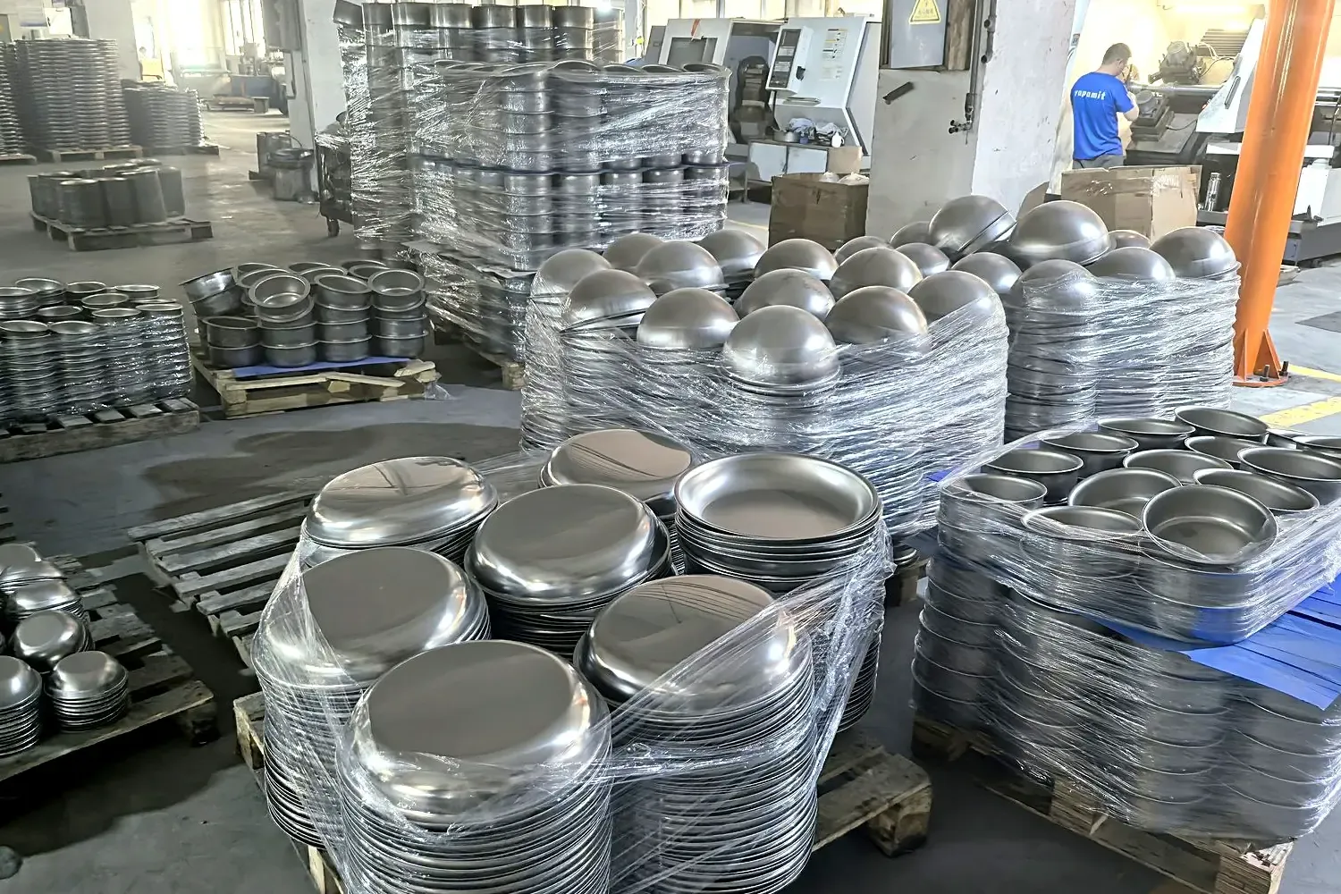 Spun carbon steel wok blank at the forming line; different forming processes support different body shapes.