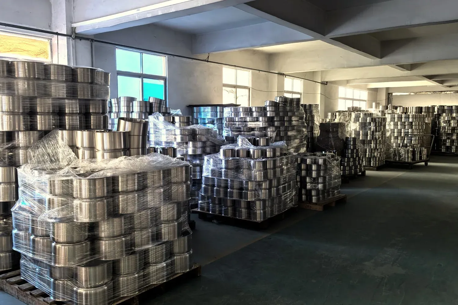 Stacks of metal cookware bodies wrapped and stored on pallets